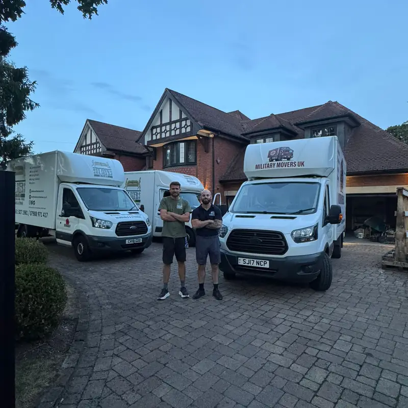 Two Military Movers UK crew members with two removal vans outside a large detached house